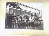 a black and white photo of a group of men riding horses