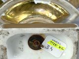 a small white bowl with a tag on it next to a gold bowl
