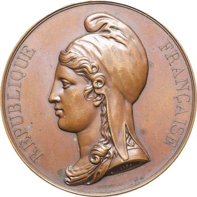 une vieille médaille en bronze sur laquelle figurent une tête de femme et une plume