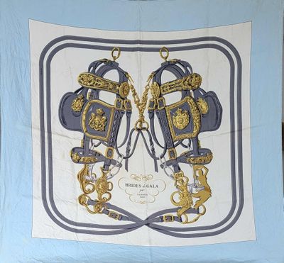 une écharpe bleue et dorée sur laquelle est représentée une paire de ciseaux