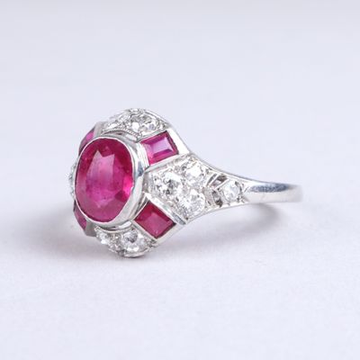 un gros plan d'une bague sertie d'un rubis et de diamants sur une surface blanche