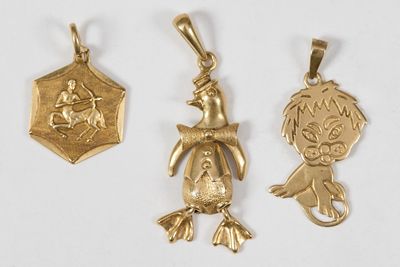 trois pendentifs en or représentant un garçon et une fille sur fond blanc