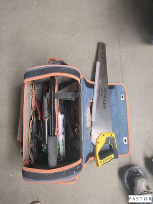 un sac à outils posé par terre, contenant des outils