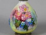un vase avec des fleurs peintes dessus, posé sur une table