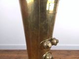 an antique brass beverage dispenser sitting on a wooden table