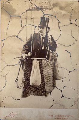 une vieille photo d'un homme en haut-de-forme, tenant un panier