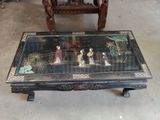 a coffee table with a painting on it and a chair in the background