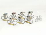 many figurines of people riding bicycles on a white surface