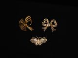 trois broches en or et un papillon sur fond noir
