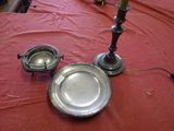 a silver plate on a table with a candle and a silver plate on the table