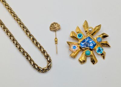 a gold chain with a blue flower brooch and a gold chain with a blue flower brooch