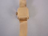 a gold watch on a white surface with a white background