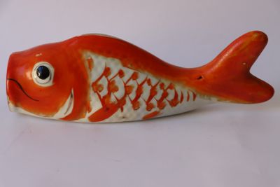 une figurine de poisson rouge et blanche posée sur une surface blanche