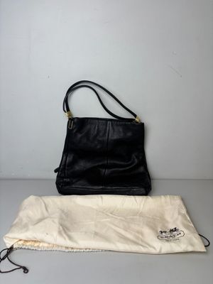 un sac à main en cuir noir avec une pochette à cordon posée sur une table