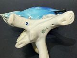 porcelain figurine of a bird on a branch with a blue sky background