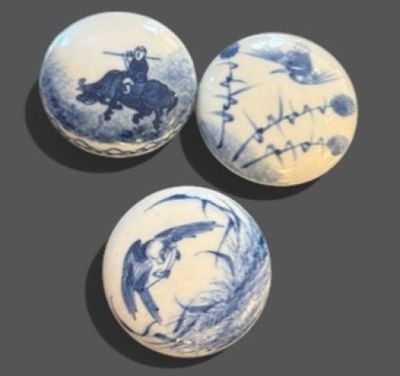three blue and white balls with designs on them sitting on a table