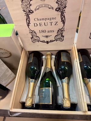 Plusieurs bouteilles de champagne se trouvent dans une caisse en bois posée sur une table