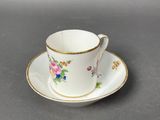 a white cup and saucer with a floral design on it