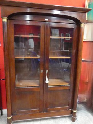une armoire en bois avec des portes vitrées dans une pièce dont l'un des murs est rouge