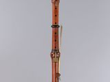 a wooden clarinet with a black and gold handle on a clear surface