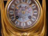 a gold clock with roman numerals on the face