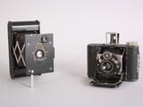 two old cameras sitting next to each other on a white surface