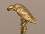 une statue en or représentant un oiseau perché sur une souche d'arbre