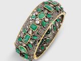 un gros plan sur un bracelet orné de pierres vertes et de diamants