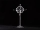 a clear glass cross on a black surface with a black background