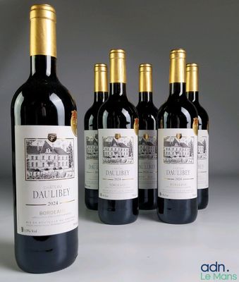 quatre bouteilles de vin rouge sont alignées sur une table