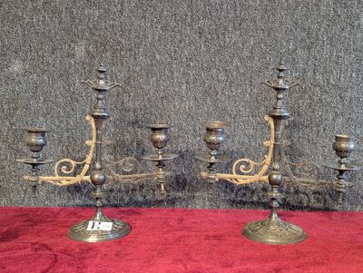 deux chandeliers anciens en laiton posés sur une nappe rouge