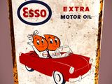 un panneau indiquant « Esso Extra Motor Oil » au bord de la route
