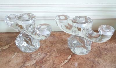 une paire de bougeoirs en verre transparent posés sur une table en marbre
