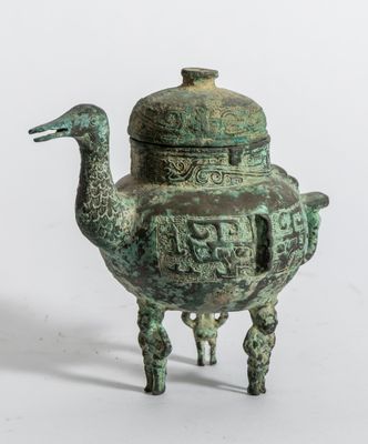 une vieille théière en bronze surmontée d'un oiseau