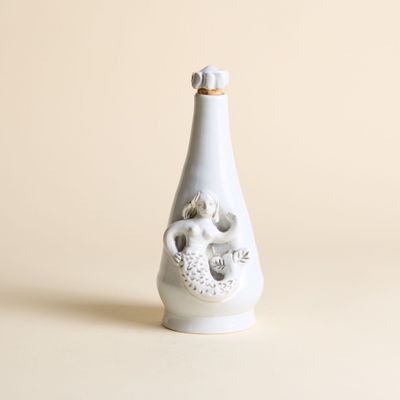 un vase blanc orné d'un crâne, posé sur une table