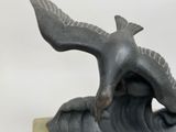 a statue of a bird that is flying over a wave