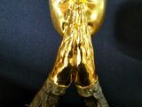 a gold statue of a man with his hands folded over his face