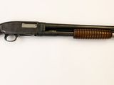 un vieux fusil posé sur une surface blanche, muni d'une crosse en bois