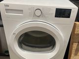 une machine à laver blanche posée sur un plan de travail, à côté d'une caisse en bois