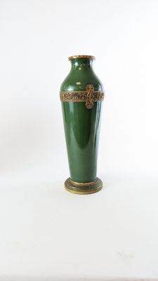 un vase vert posé sur une table, sur fond blanc