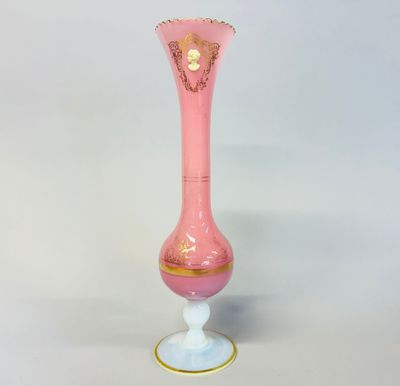 pink glass vase with gold trim on a white pedestal