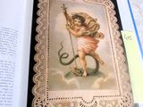 an open book with a picture of a cupid holding a snake
