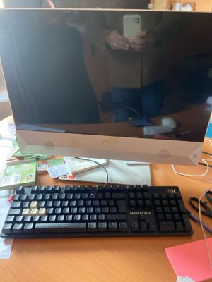 un écran d'ordinateur et un clavier posés sur un bureau, à côté d'un téléphone portable