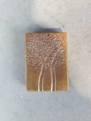 un petit objet en métal sur lequel est représenté un arbre