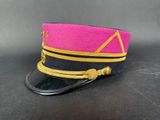 pink and black military hat with gold trim on a black surface