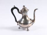 an antique silver teapot with a black handle on a white background