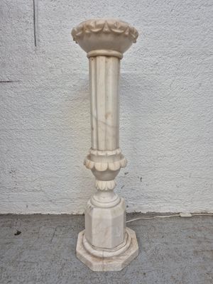 a white vase on the ground next to a white wall