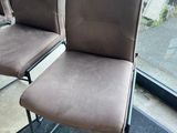 two brown chairs sitting next to each other in a room