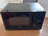 a black microwave sitting on a wooden table in a room