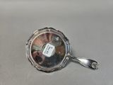 an antique silver plate with a spoon and spoon rest on a table